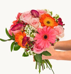 Vibrant floral bouquet featuring pink roses, orange gerberas, and greenery, ideal for celebrations.
