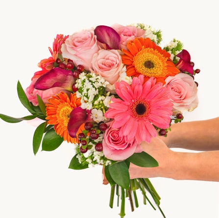 Vibrant floral bouquet featuring pink roses, orange gerberas, and greenery, ideal for celebrations.