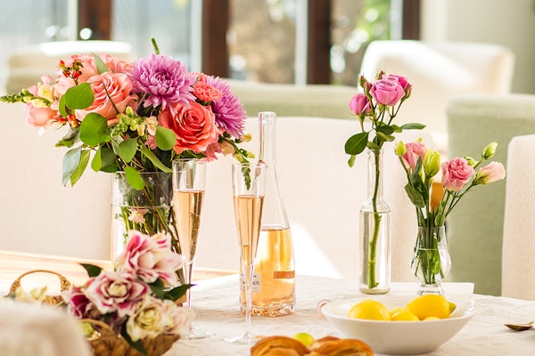 Bright floral arrangements with pink and orange blooms on a festive dining table.