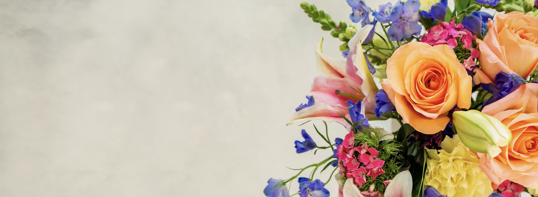 Vibrant floral arrangement featuring peach roses, lilies, and colorful seasonal blooms.