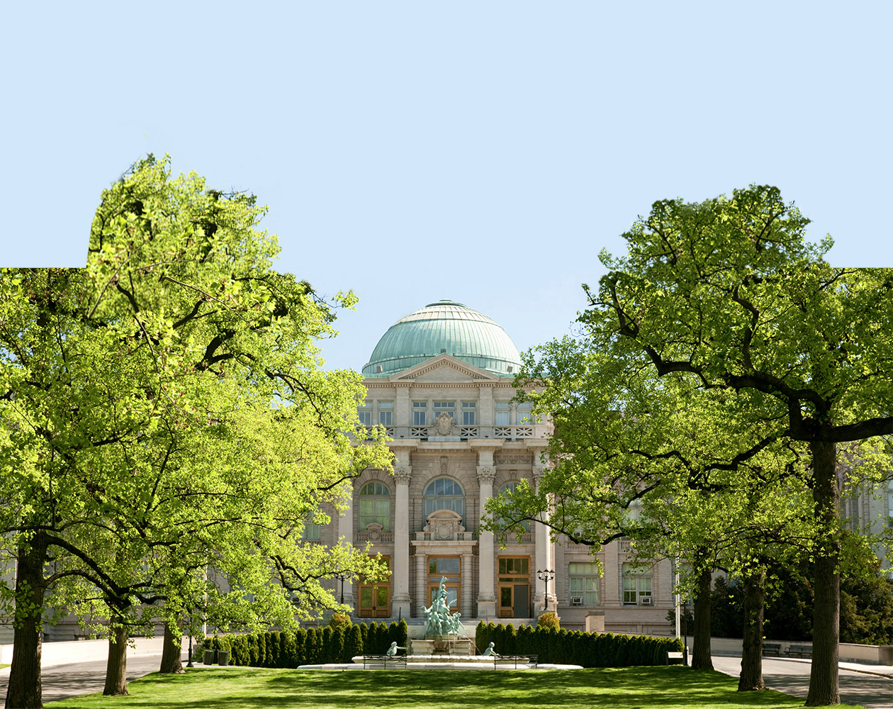 Elegant architecture with lush green trees framing a grand building, showcasing classic design.
