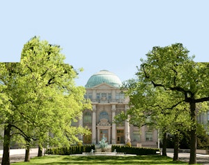 Elegant architecture with lush green trees framing a grand building, showcasing classic design.