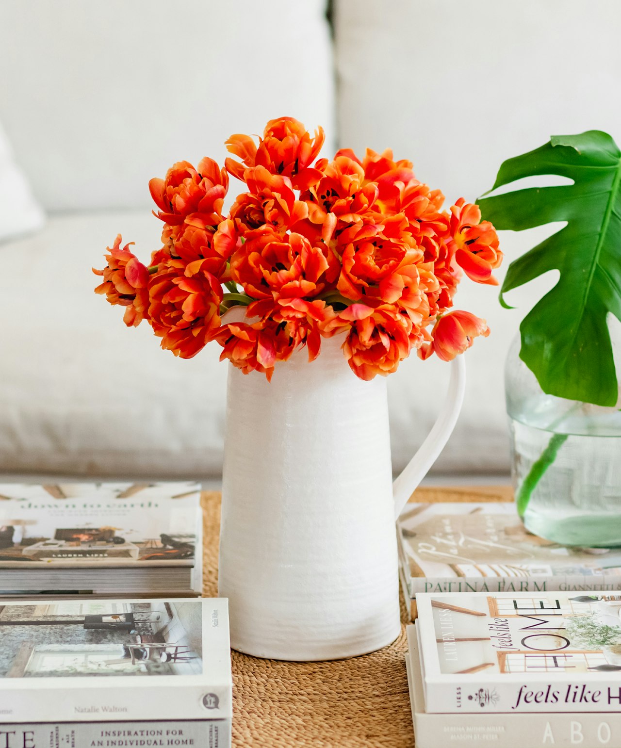 Vibrant orange tulips elegantly arranged in a white pitcher vase, enhancing any decor.