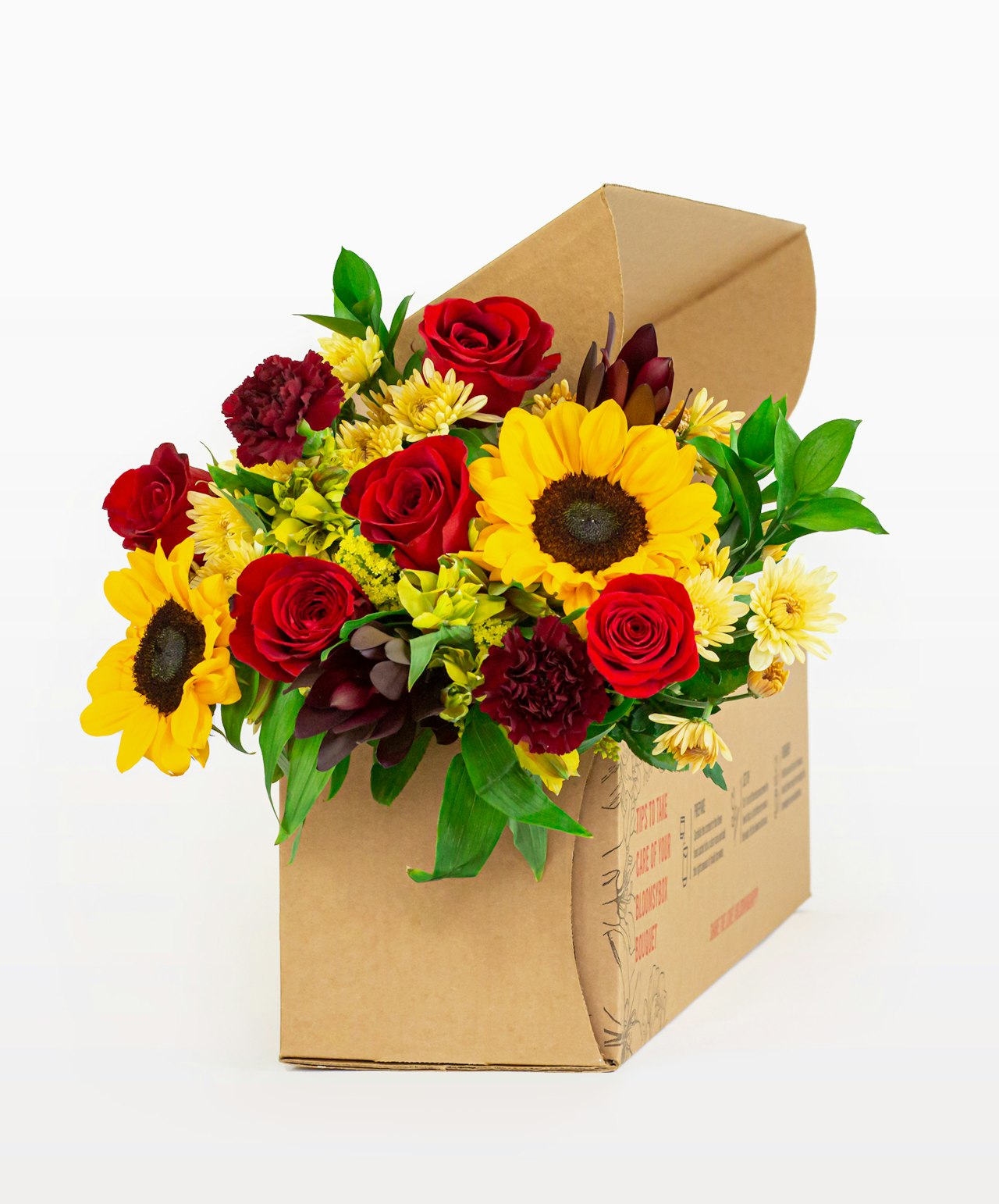 Bright floral arrangement featuring sunflowers, red roses, and vibrant greenery in a decorative box.