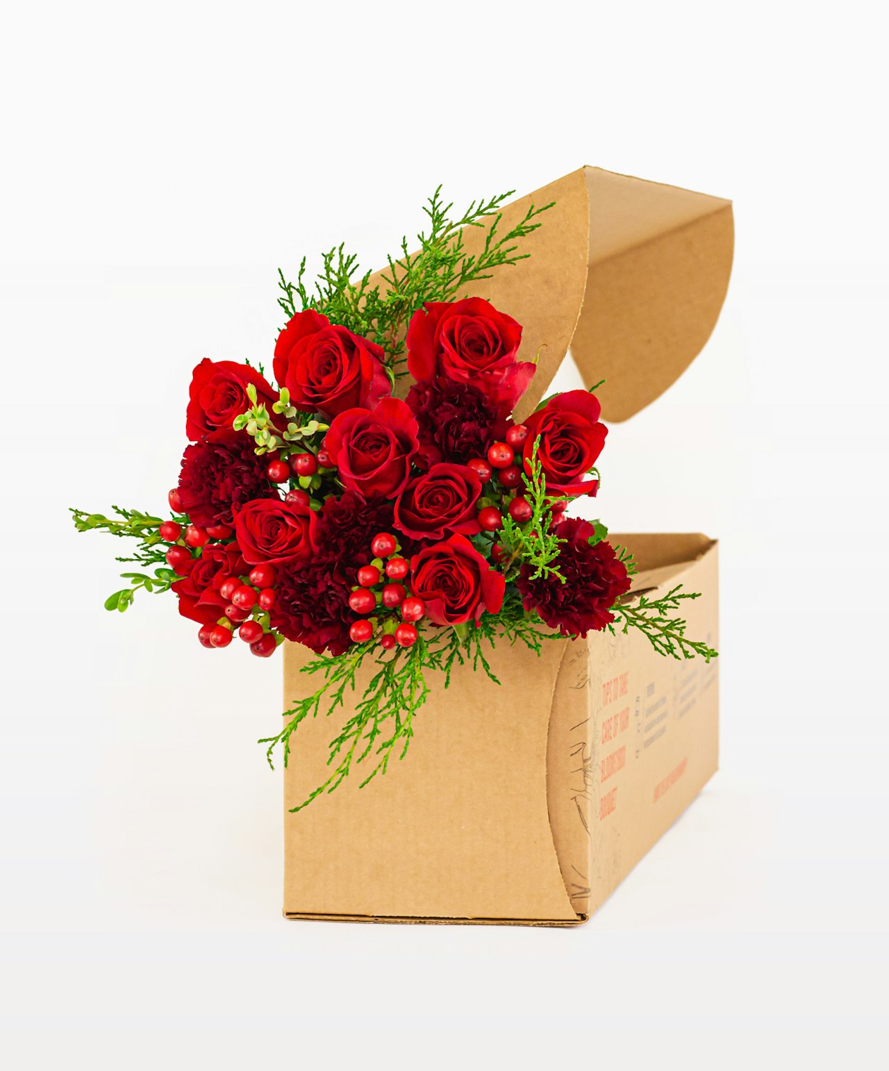 Vibrant red roses and seasonal greenery beautifully arranged in a chic floral gift box.