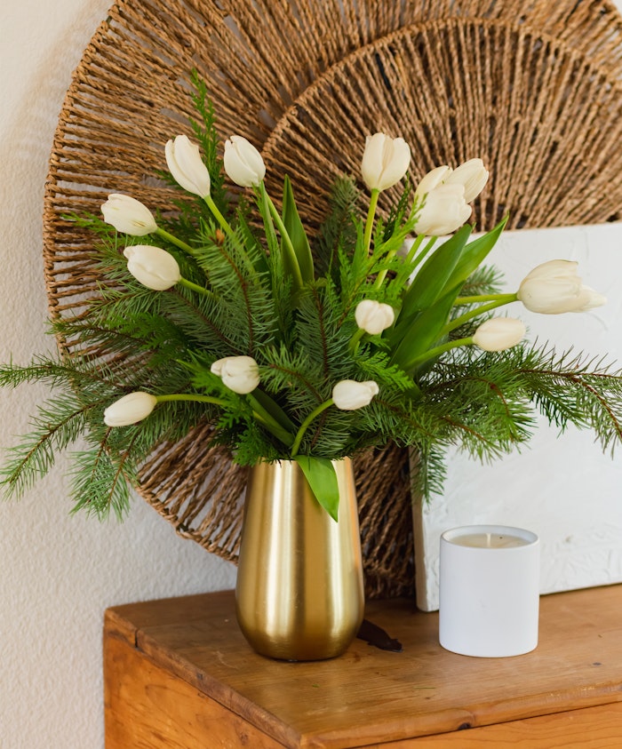 Elegant white tulips paired with greenery in a chic gold vase, adding sophistication to any decor.