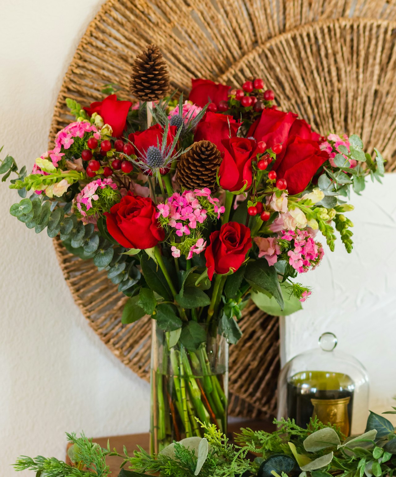 Vibrant bouquet of red roses, pink flowers, and greenery in a chic vase, perfect for decor.