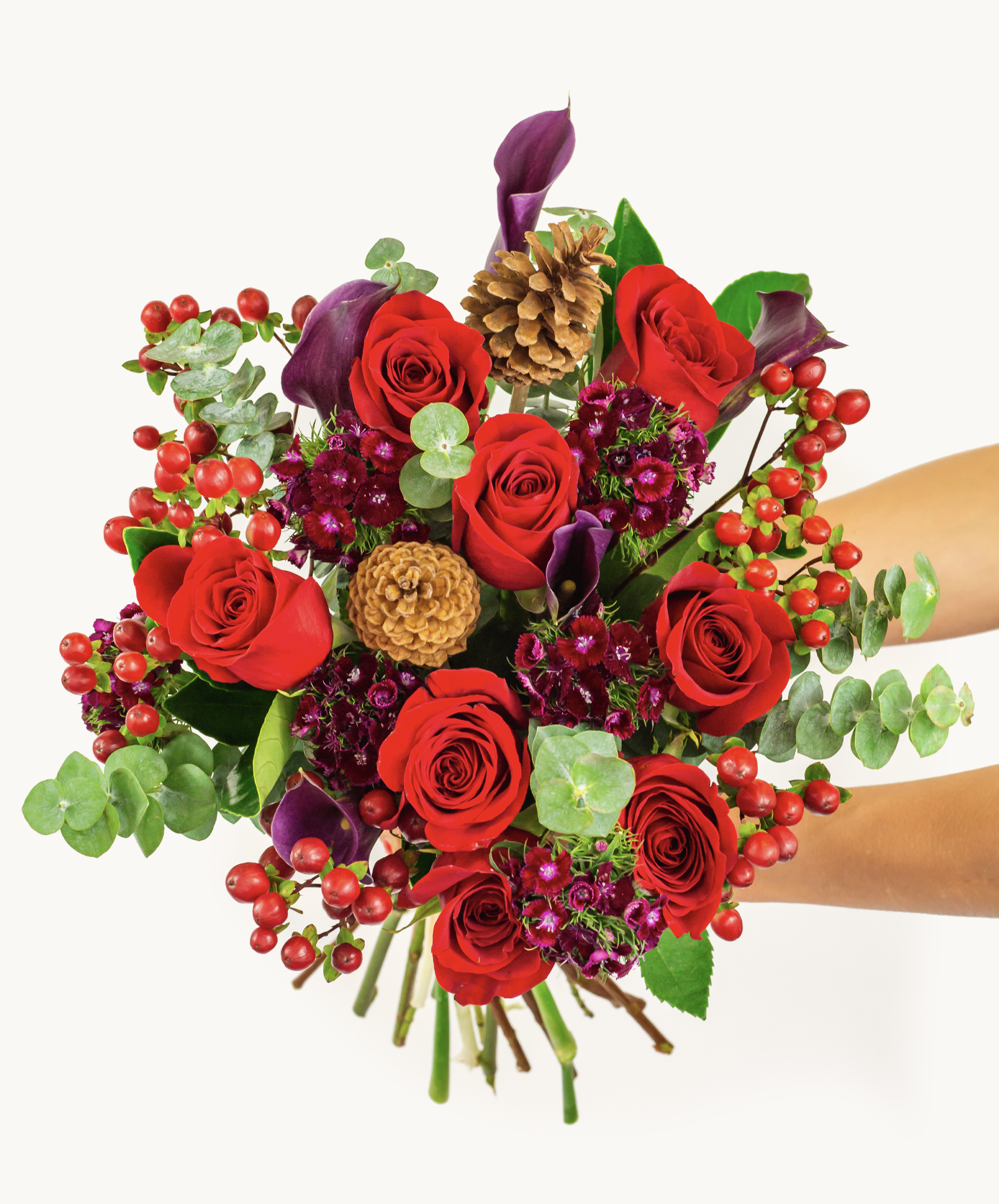 Vibrant bouquet featuring red roses, pinecones, and seasonal greens, ideal for gifting.
