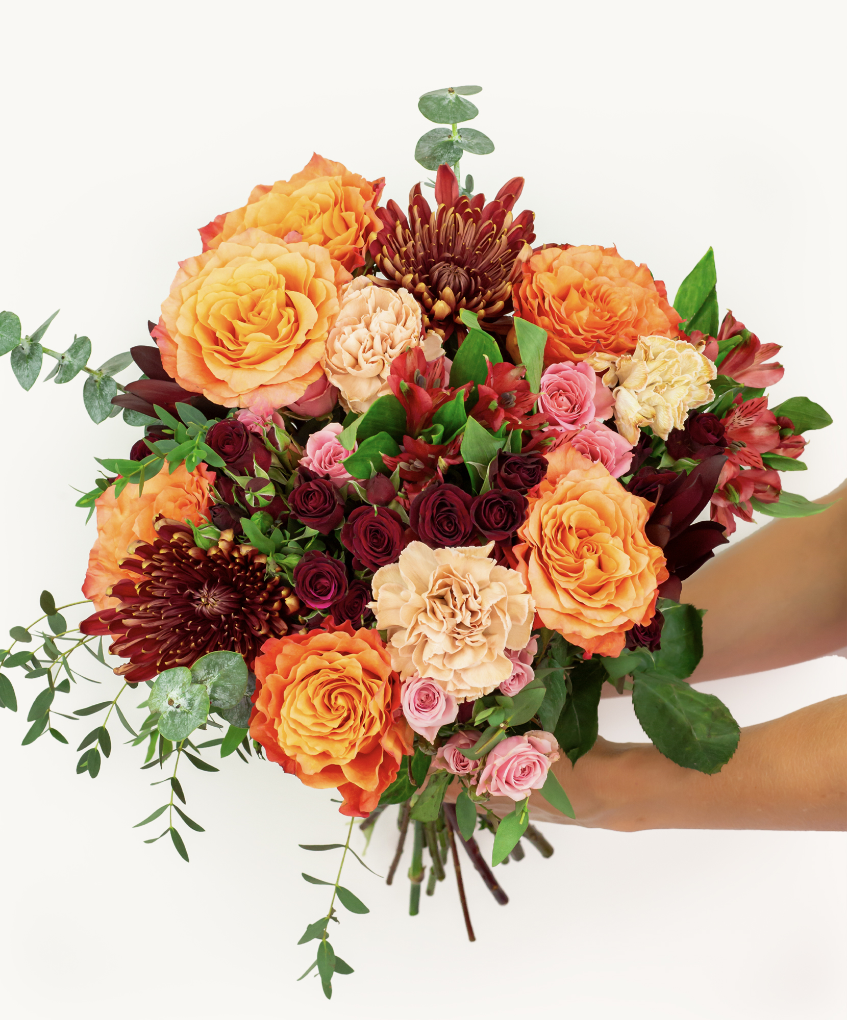 Vibrant autumn bouquet featuring orange roses, burgundy chrysanthemums, and lush greenery.