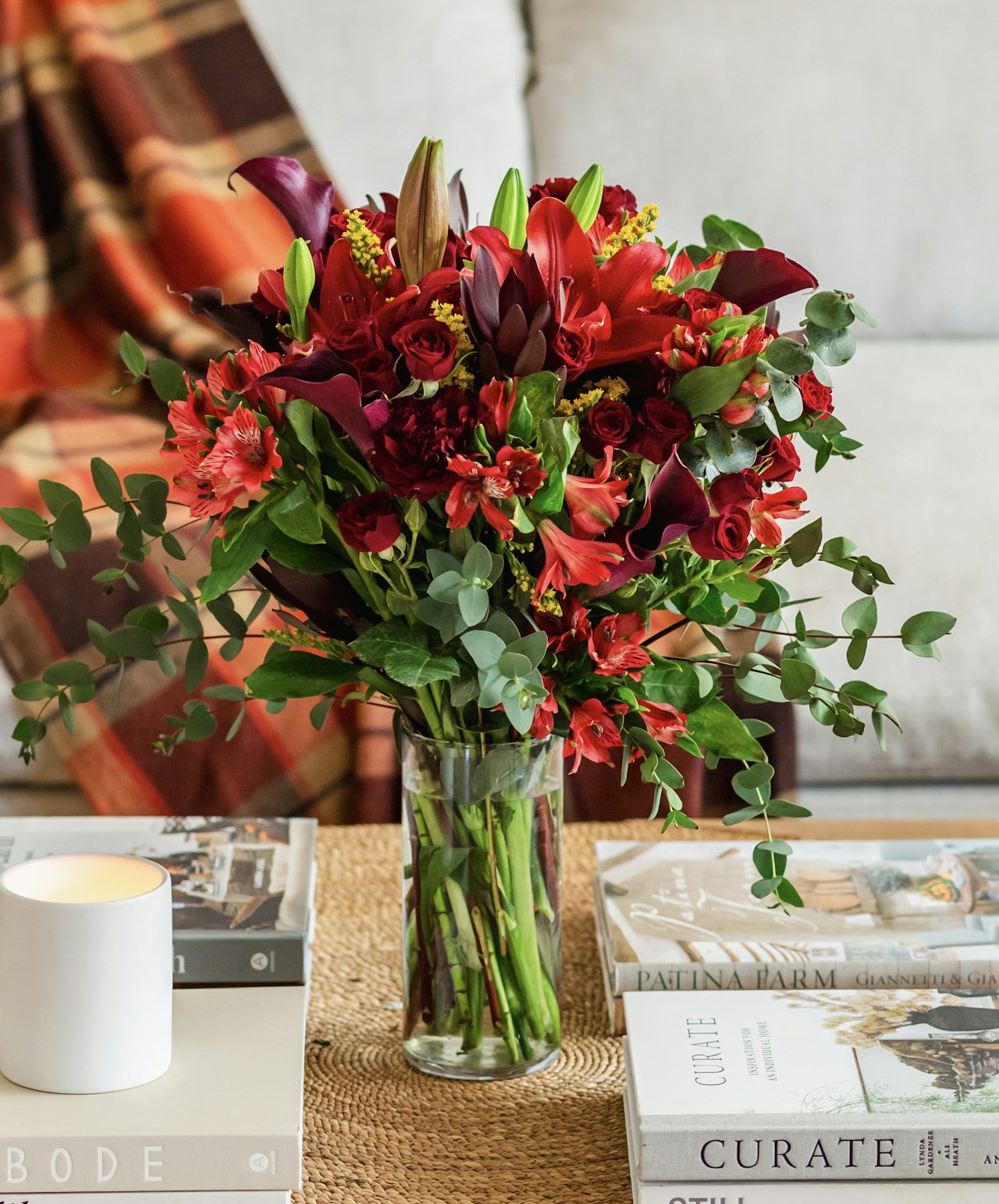 Vibrant floral arrangement featuring red lilies, roses, and greenery in a stylish vase.