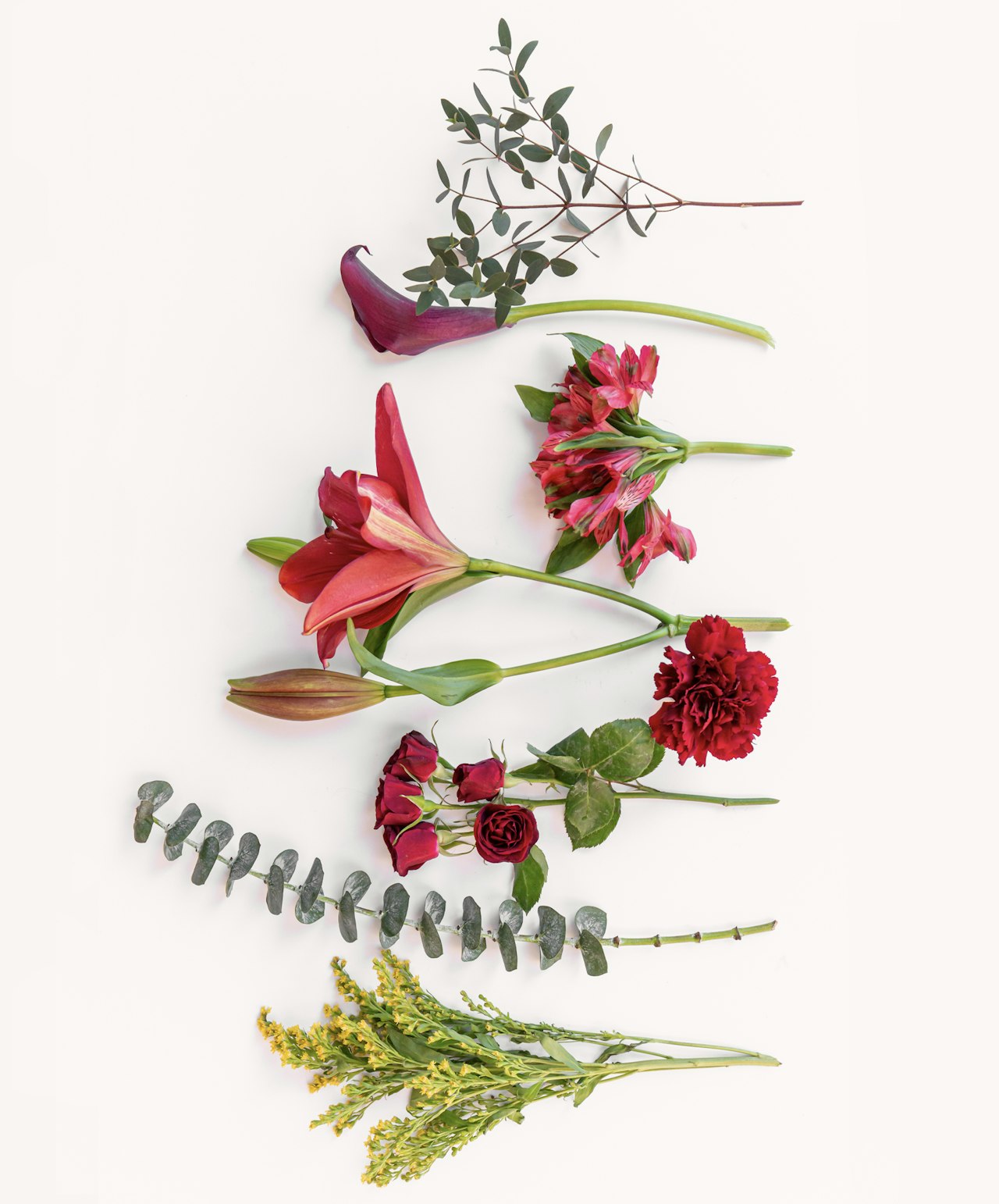 A vibrant floral arrangement featuring lilies, roses, eucalyptus, and alstroemerias on white.