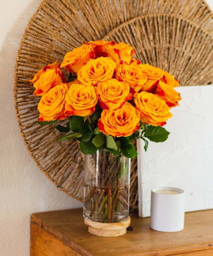 Vibrant orange and yellow roses arranged in a clear vase, radiating warmth and joy.