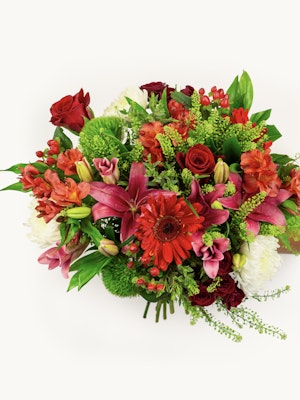Vibrant mixed floral bouquet featuring red roses, pink lilies, and lush greenery.
