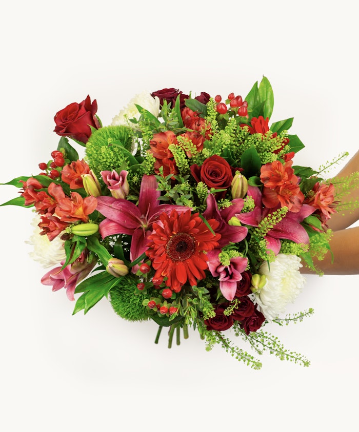 Vibrant mixed floral bouquet featuring red roses, pink lilies, and lush greenery.