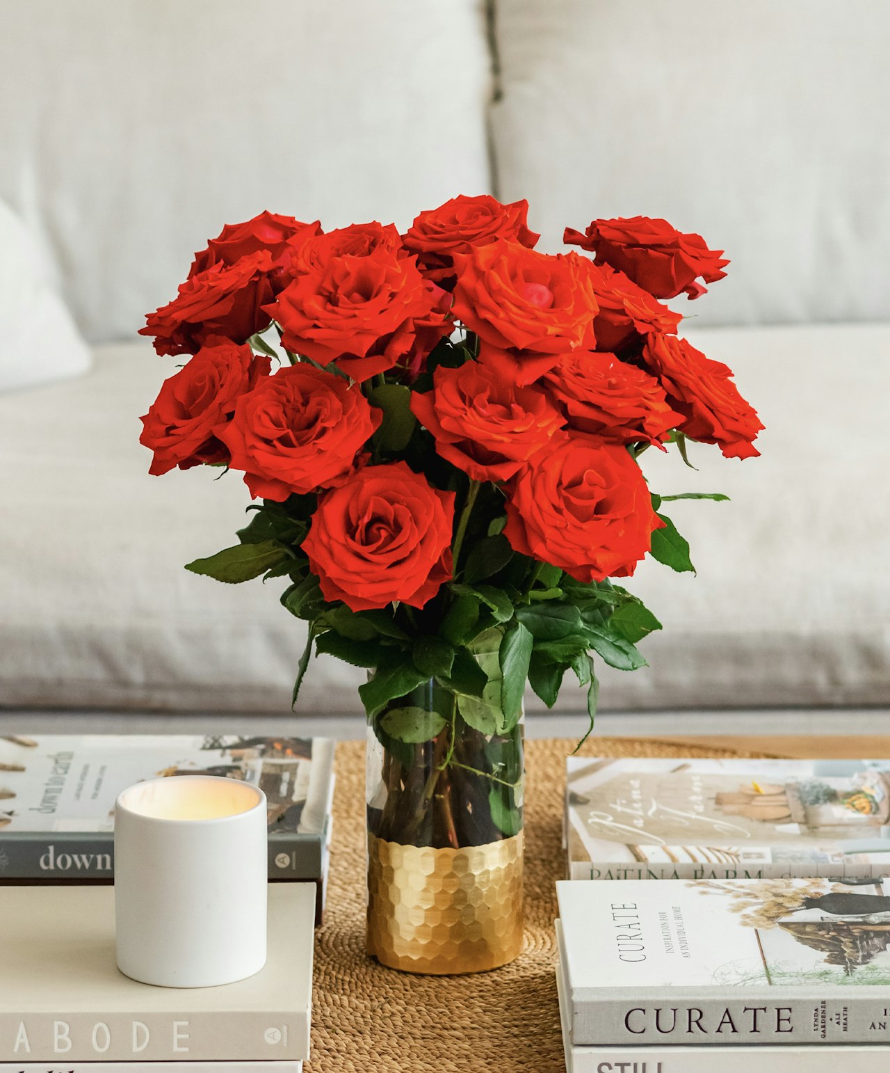 Vibrant red roses arranged elegantly in a golden vase, enhancing a stylish living room setting.