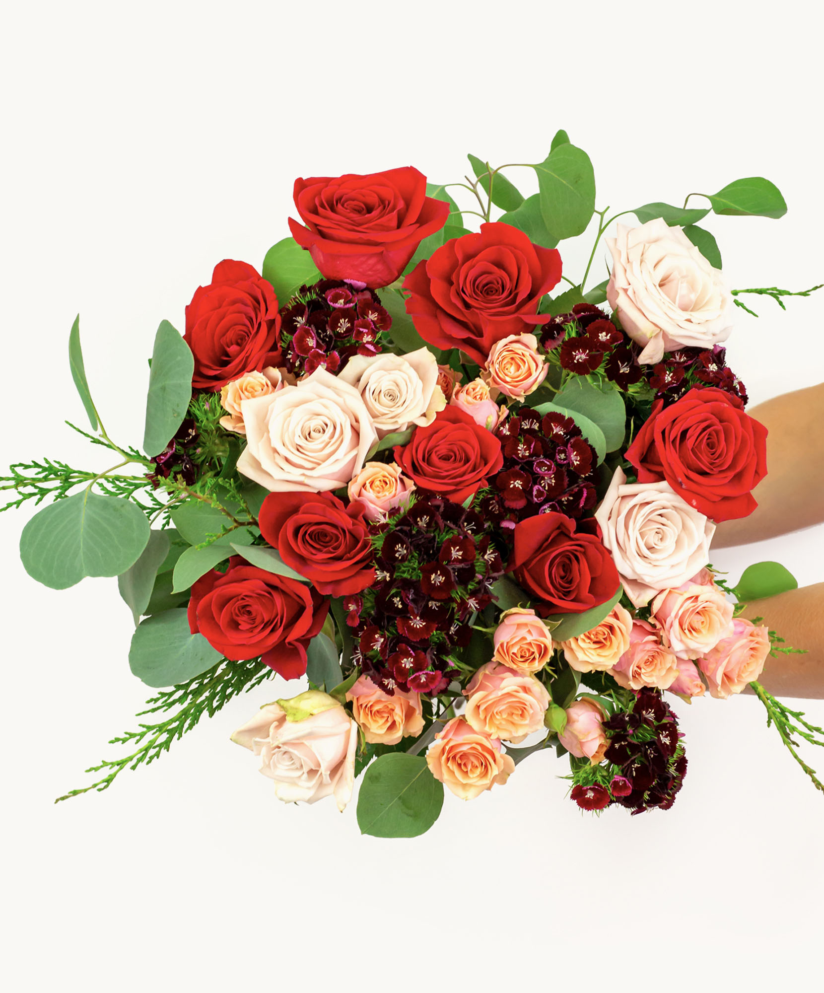 Vibrant floral bouquet featuring red, pink, and cream roses surrounded by lush greenery.