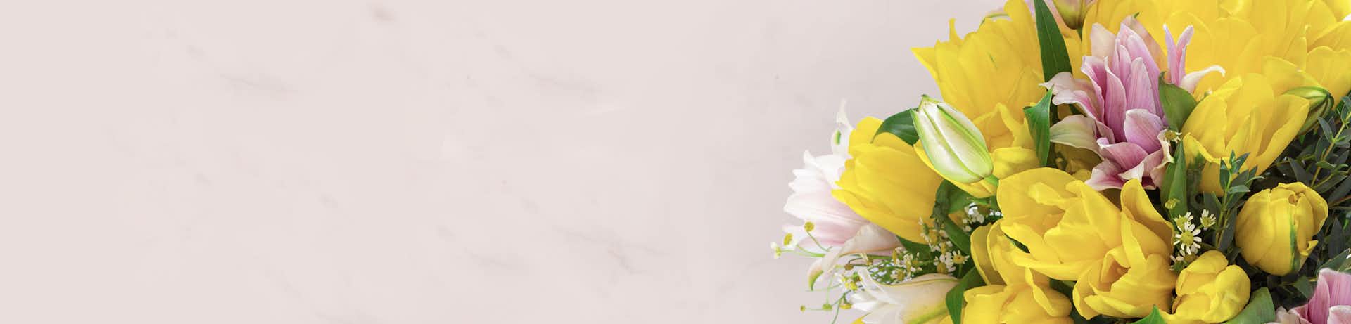 Bright yellow tulips and soft pink flowers in a vibrant spring bouquet, perfect for celebrations.