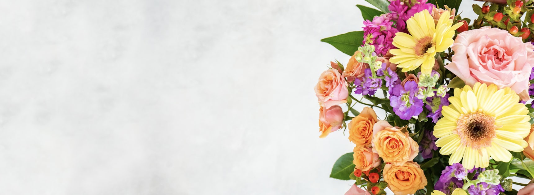 Vibrant floral arrangement featuring yellow gerbera daisies, pink roses, and colorful blooms.
