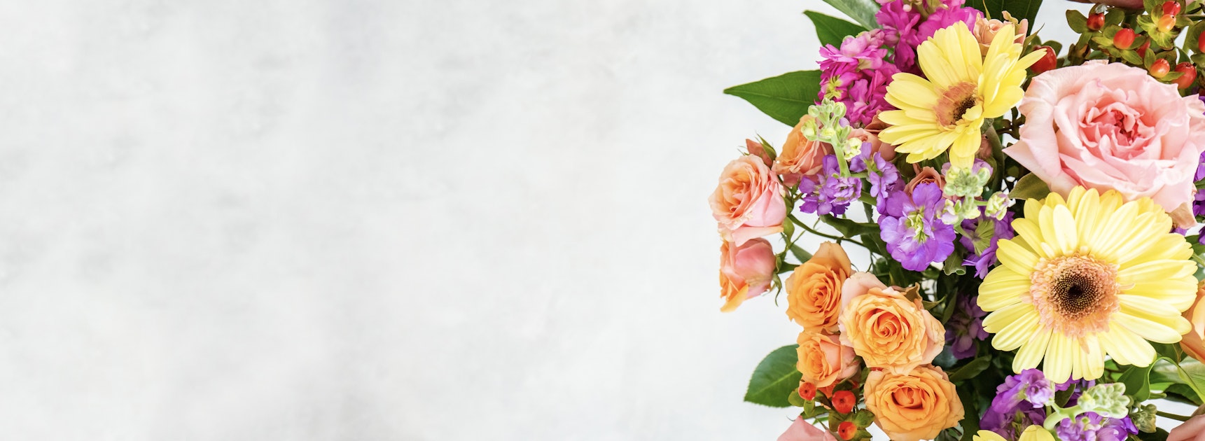 Vibrant floral arrangement featuring yellow gerbera daisies, pink roses, and colorful blooms.