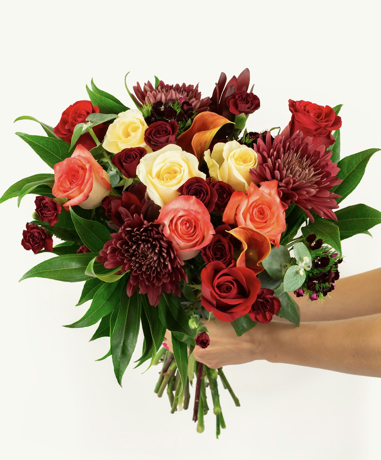 Vibrant bouquet featuring red, orange, and cream roses with lush greenery, perfect for celebrations.