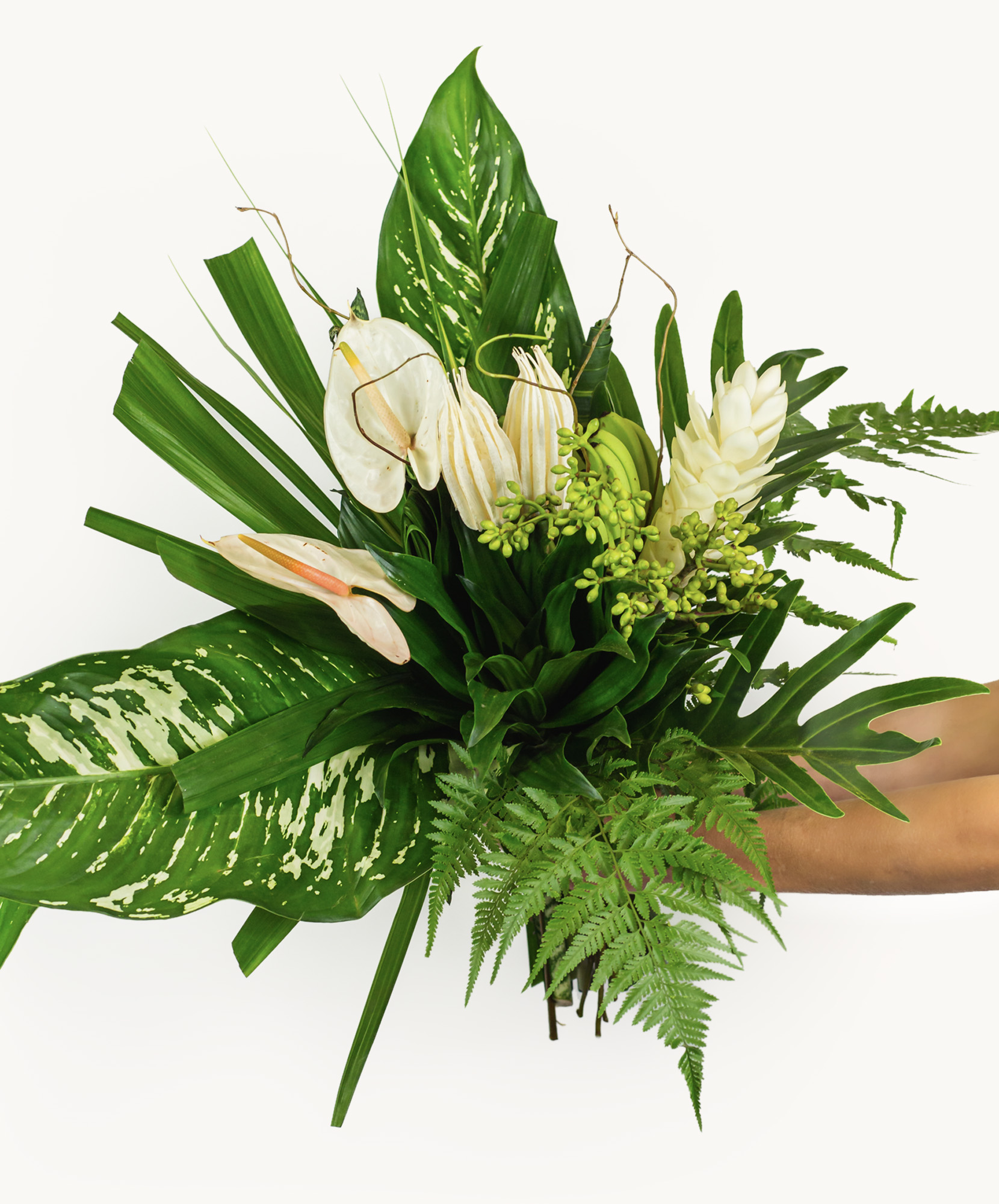 Lush green bouquet featuring white tropical flowers and vibrant foliage, elegantly arranged.