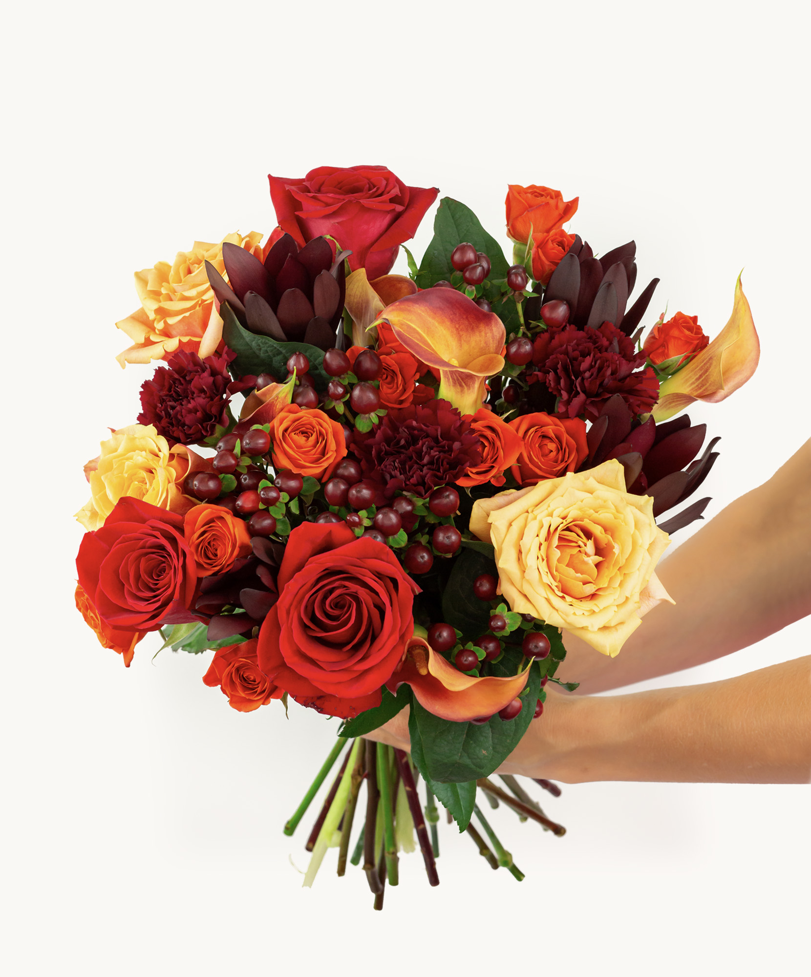 Vibrant bouquet of red and orange roses, accented with green foliage and seasonal blooms.