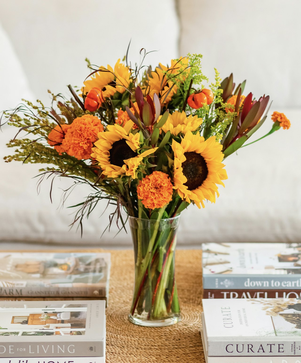 Vibrant bouquet of sunflowers and orange blooms in a clear vase, enhancing any living space.