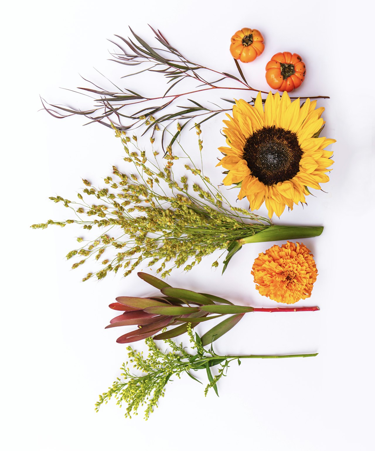 Vibrant autumn floral arrangement featuring sunflowers, marigolds, and decorative pumpkins.