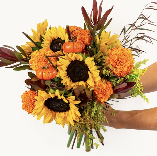 Vibrant autumn bouquet featuring sunflowers, marigolds, and seasonal pumpkins.