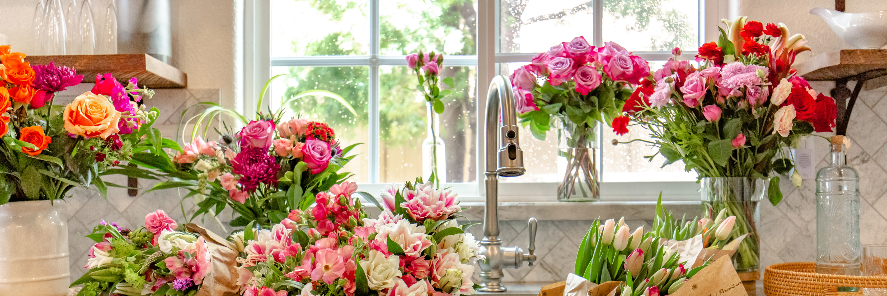 Vibrant floral display with colorful roses and lilies by a sunny kitchen window.