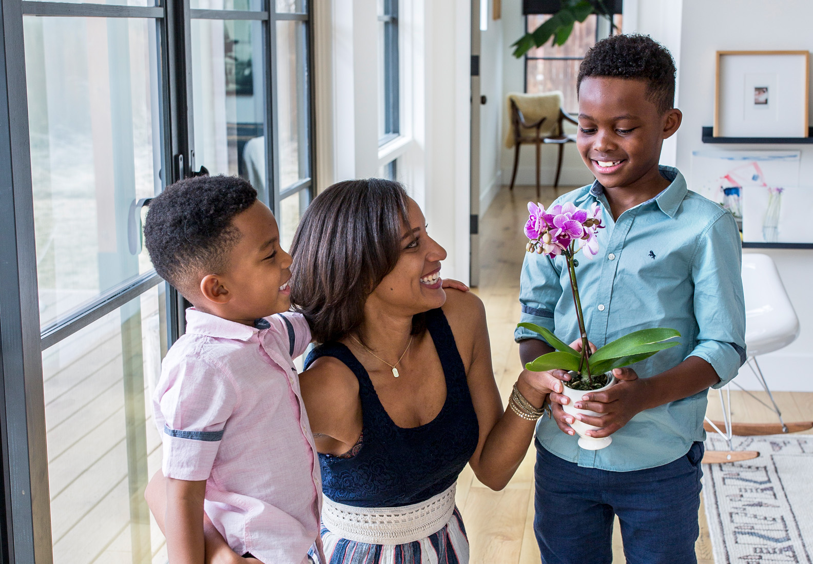 Cherished family moment with a mother and her two sons enjoying a beautiful orchid plant.