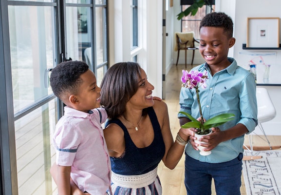 Cherished family moment with a mother and her two sons enjoying a beautiful orchid plant.