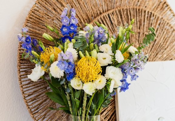 Vibrant floral arrangement featuring yellow, blue, and white blooms in a decorative vase.