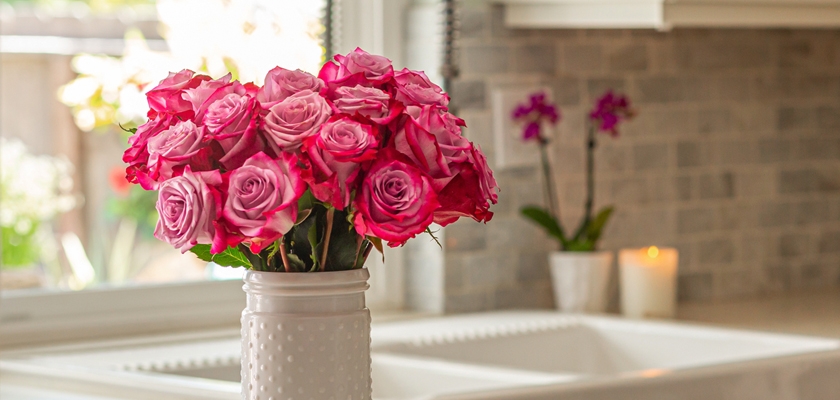 A vibrant arrangement of pink roses in a ceramic vase, brightening a kitchen space.