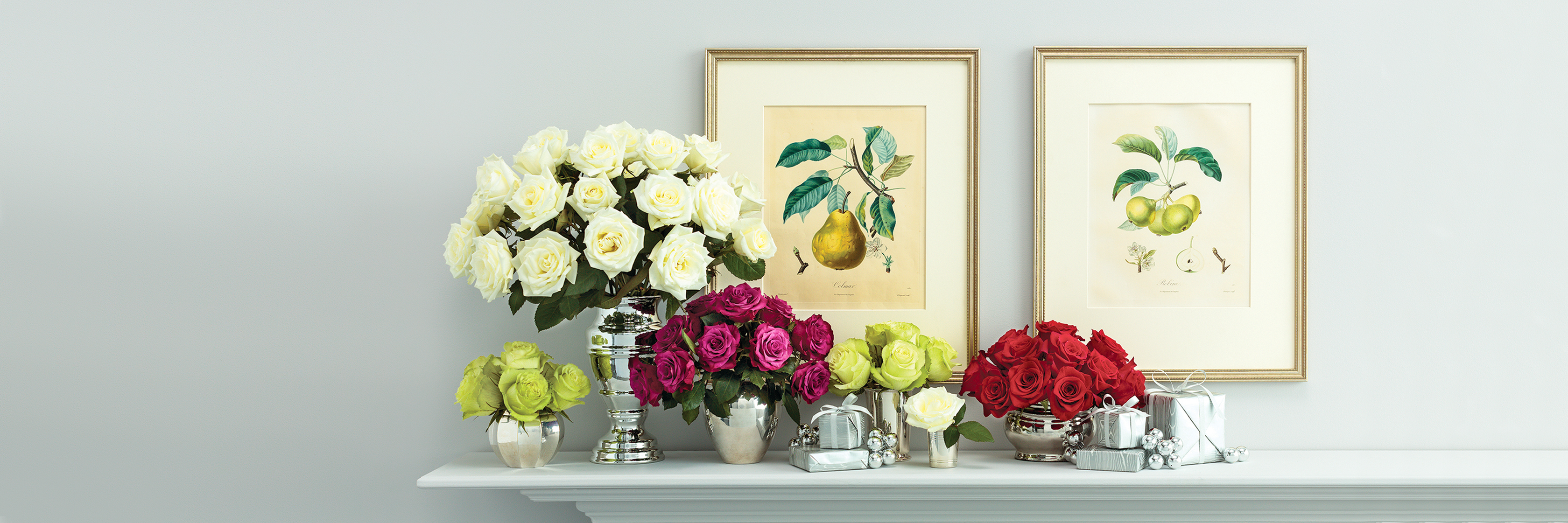 Elegant floral display featuring white, pink, and red roses on a mantel with vintage artwork.