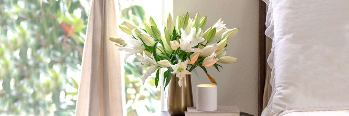 Elegant white lilies in a chic vase, enhancing a serene bedroom ambiance.