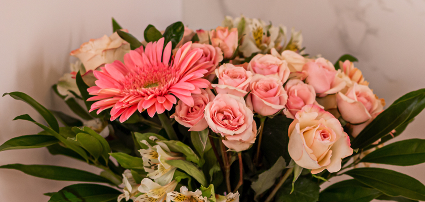 A vibrant floral arrangement featuring pink roses and a striking gerbera daisy.