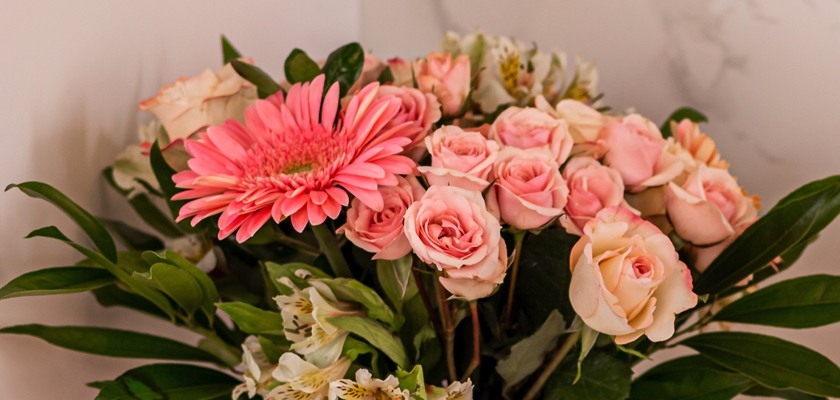 A vibrant floral arrangement featuring pink roses and a striking gerbera daisy.