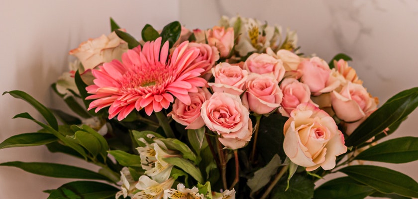 A vibrant floral arrangement featuring pink roses and a striking gerbera daisy.