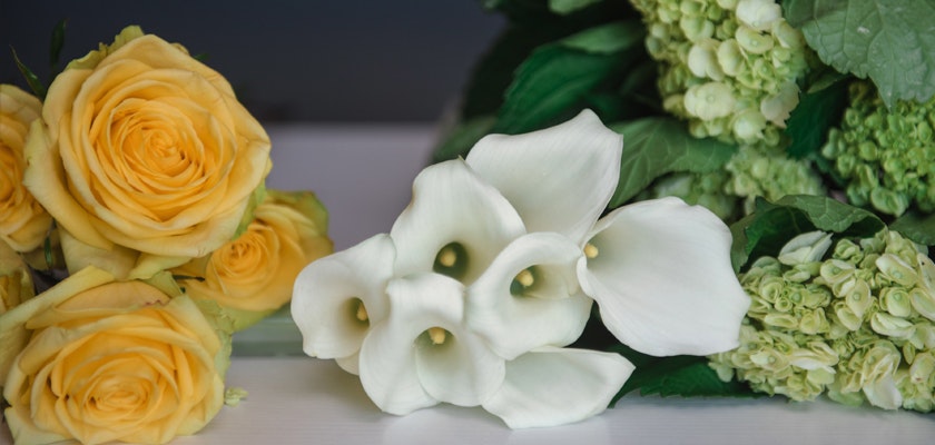 A lovely arrangement of yellow roses and elegant white calla lilies with greenery.