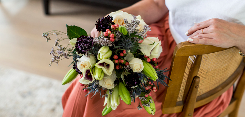 Elegant floral bouquet featuring white roses, vibrant lilies, and colorful berries.
