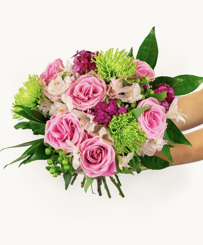 Delicate bouquet featuring pink roses, green pom-poms, and lush greenery, ideal for celebrations.