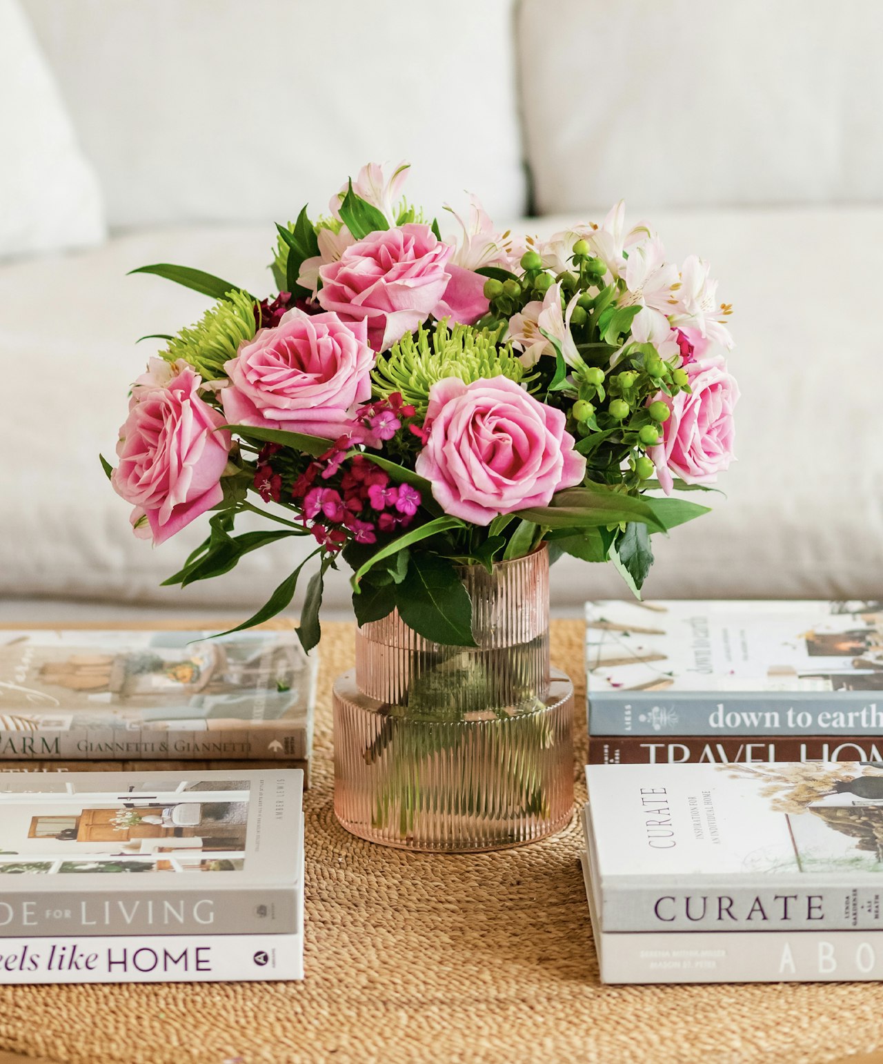Charming pink rose bouquet with greenery, elegantly displayed on a coffee table with books.