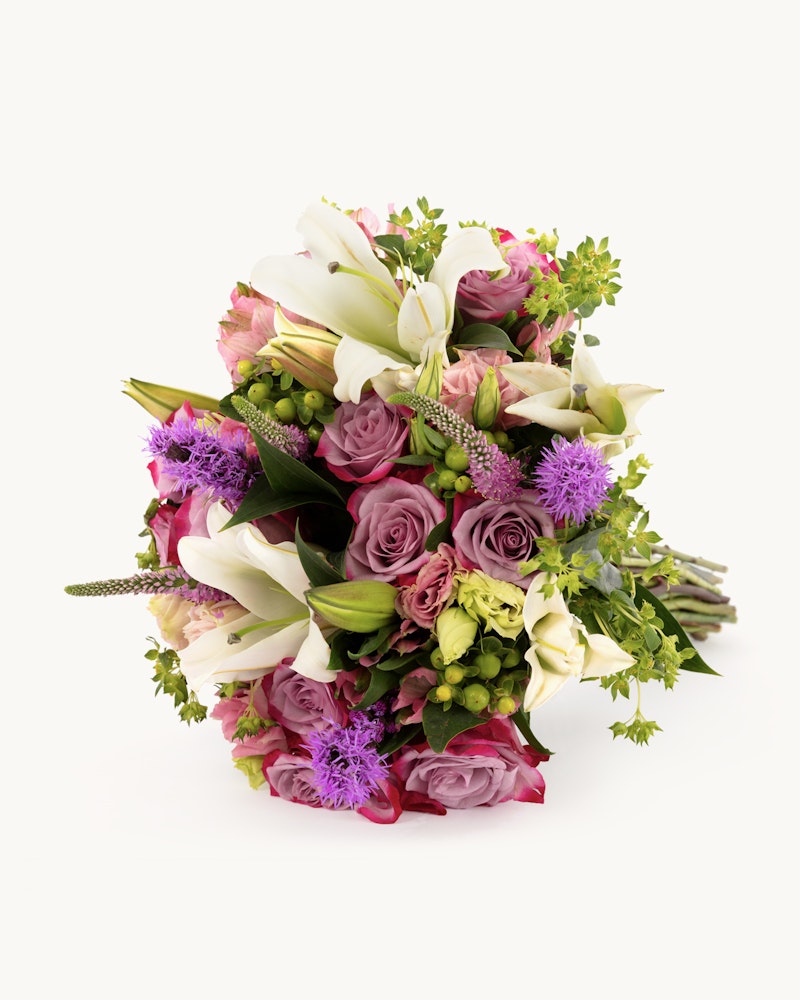 Vibrant bouquet of flowers featuring white lilies, pink and green roses, purple accents, and lush greenery against a clean white background.