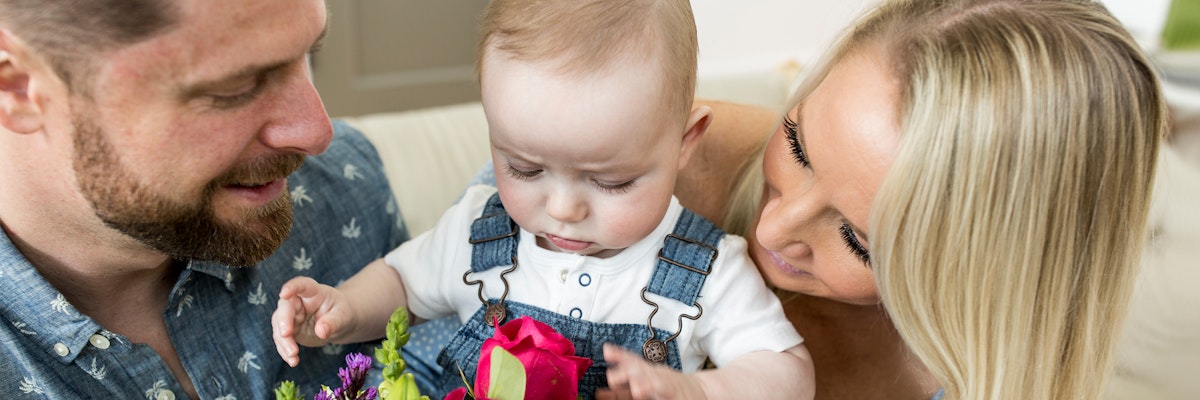 A joyful family moment with a baby exploring a colorful flower bouquet, surrounded by love.