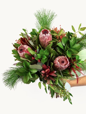 Vibrant bouquet featuring proteas, greenery, and seasonal accents, ideal for any celebration.
