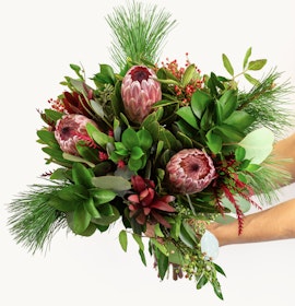Vibrant bouquet featuring proteas, greenery, and seasonal accents, ideal for any celebration.