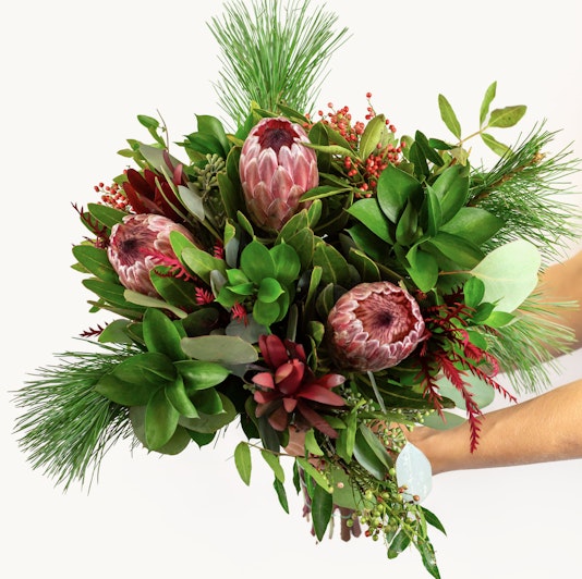 Vibrant bouquet featuring proteas, greenery, and seasonal accents, ideal for any celebration.