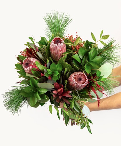 Vibrant bouquet featuring proteas, greenery, and seasonal accents, ideal for any celebration.