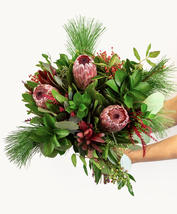 Vibrant bouquet featuring proteas, greenery, and seasonal accents, ideal for any celebration.
